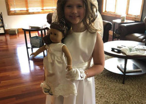 nicole's daughter and her doll wearing matching communion dresses made from her wedding dress